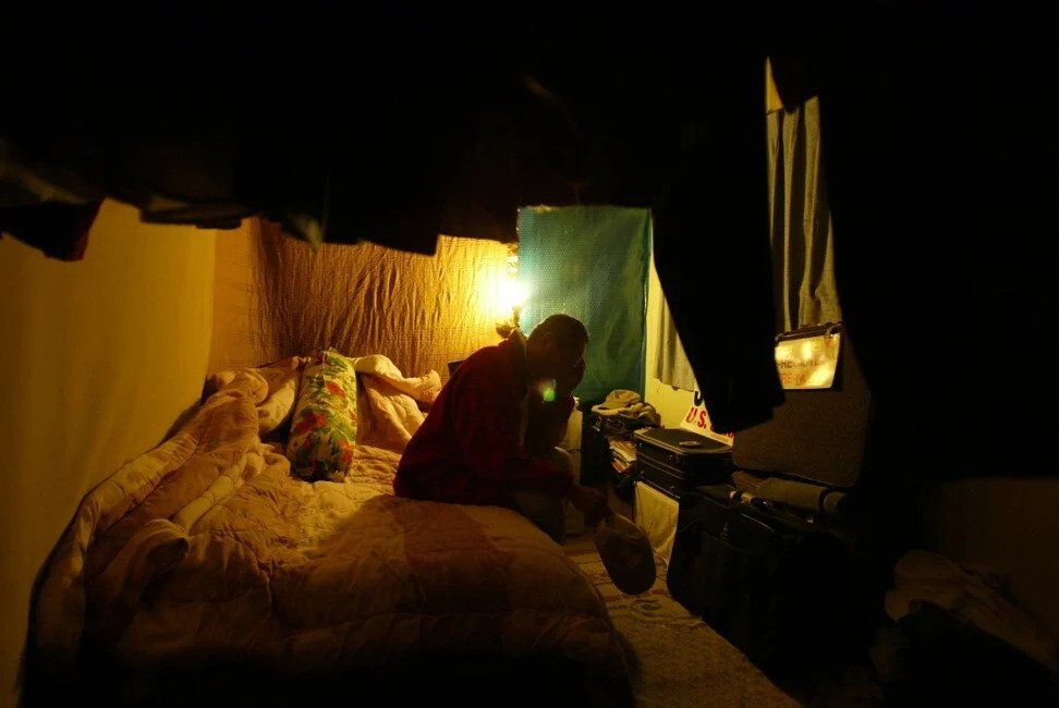 Ngoy sits on the bed in a room that is part of a friend’s trailer in Long Beach, California, in November 2004. Photo: Los Angeles Times via Getty Images